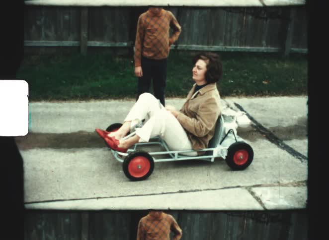 The boy helps his mom ride in the kart