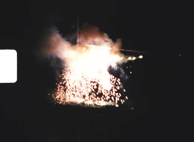 Incandescent sparks falling from metal structure during nighttime display