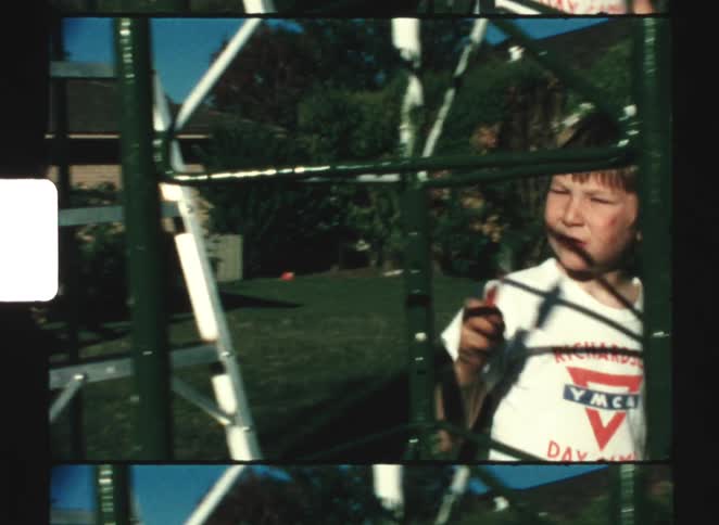 Two kids painting a steel tower in their backyard on a sunny day changing it from white to black