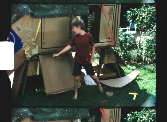 Two kids climbing out of a fort