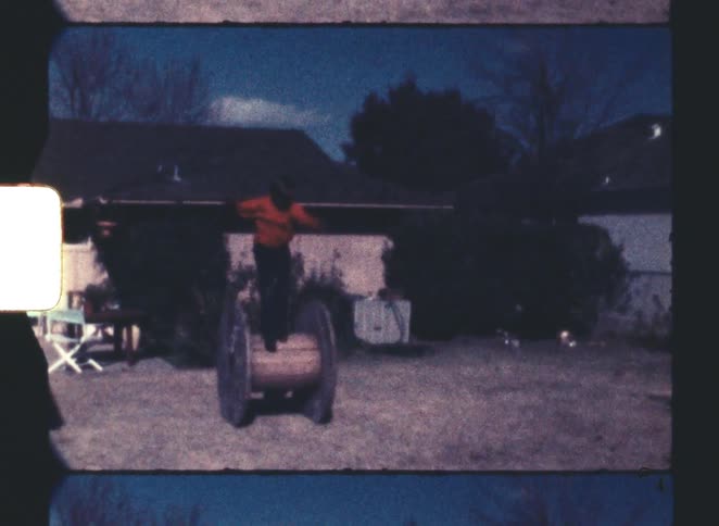 A kid walking on a wire spool