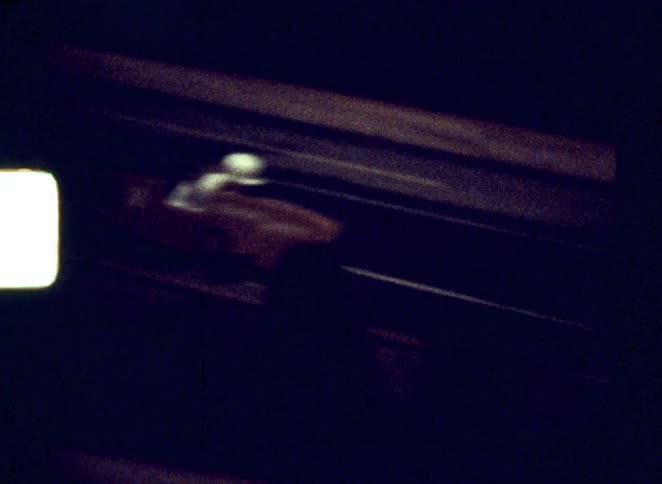 A lone rider travels along a dark roadway at night under dim street lighting