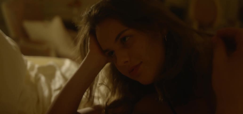 A person brushes a woman's hair in bed