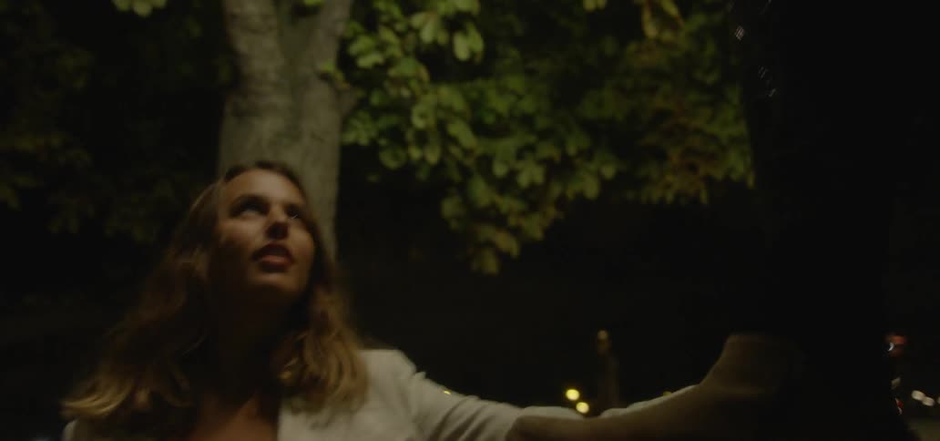 A woman circling around a man's feet at night