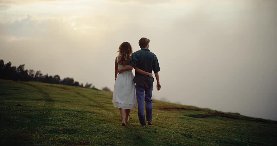 The couple hug while walking on the field