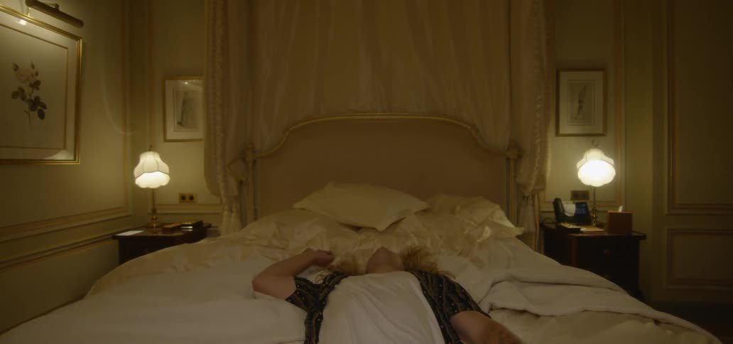 A man sits on a bed and falls back onto it