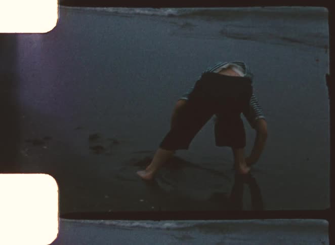 Boy digs into the wet sand on a dimly lit hazy day