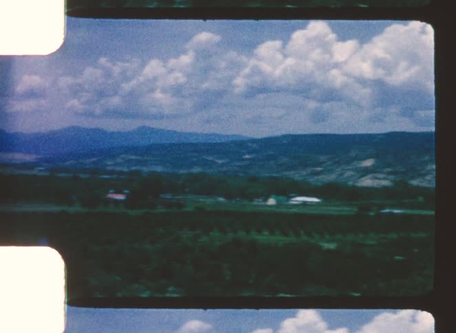 Wide landscape with hills in the background and rural areas in the foreground under a cloudy sky