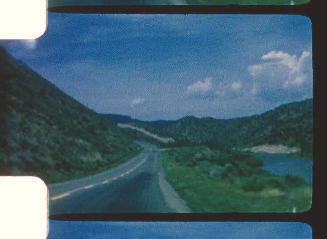 The car drives by the river and mountains