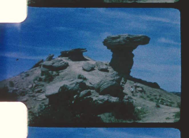 Isolated rock formation in an arid landscape under an open blue sky