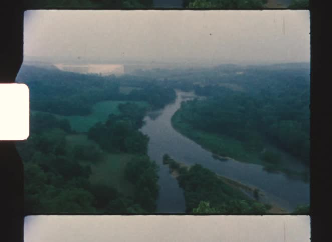 A river running through the rainforest where two river paths meet and curve into one surrounded by dense trees at midday