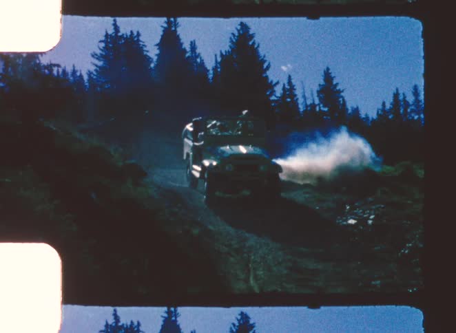 Offroad vehicle climbing a steep trail with smoke emission in a forested area at night