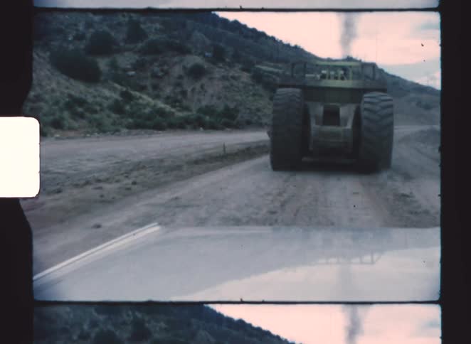 A car following a large earth moving machine
