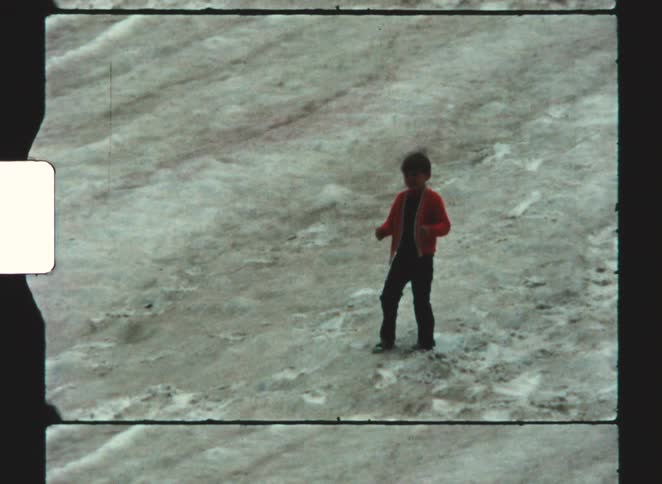 A child throwing something on a grassy hill