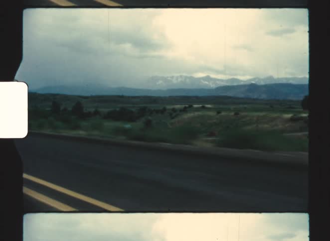 The cars travel on the long highway by the hills