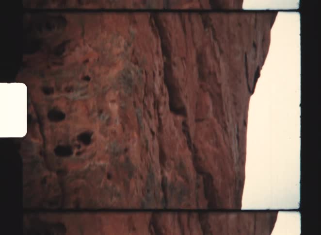 A mountain with a rugged redcolored slope standing in the wild at midday