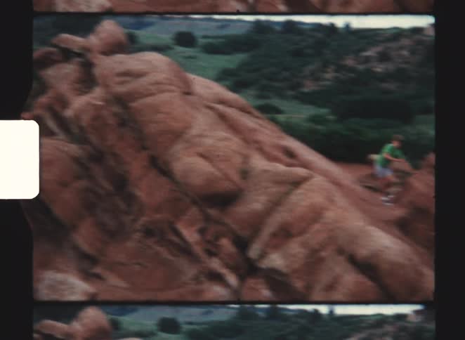 Two boys race down the side of the boulder