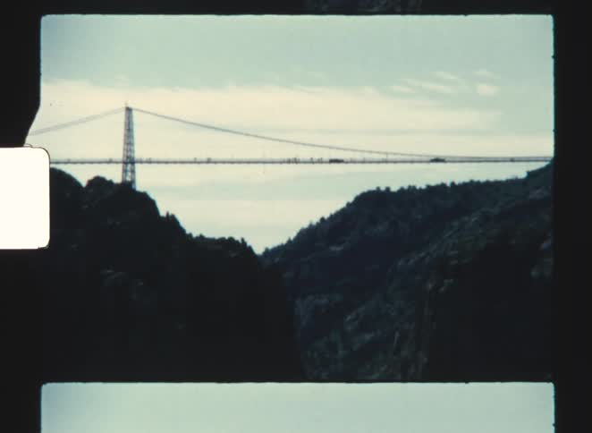 royal gorge 1970  A cable bridge visible in the distance beyond a hill set in a rural landscape at midday
