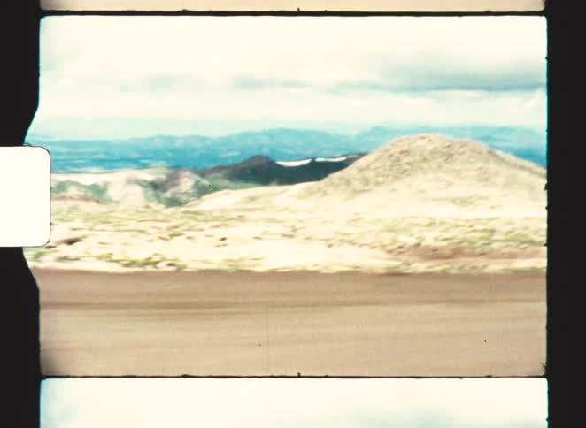 Dirt road along a mountain slope with a wide view of valleys and mountain ranges in the background