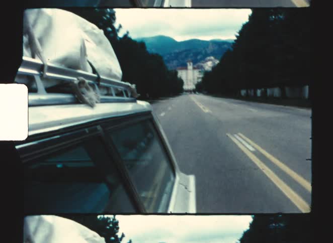 A car driving away from the broadmoor hotel in colorado springs 1970 along the freeway on a countryside road trip at midday