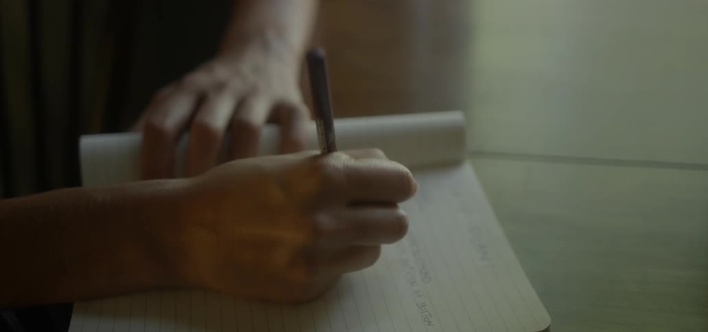 A person sitting at a table and writing in a notebook