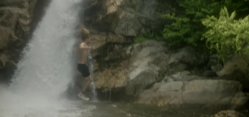 A man jumps from a cliff into the river below