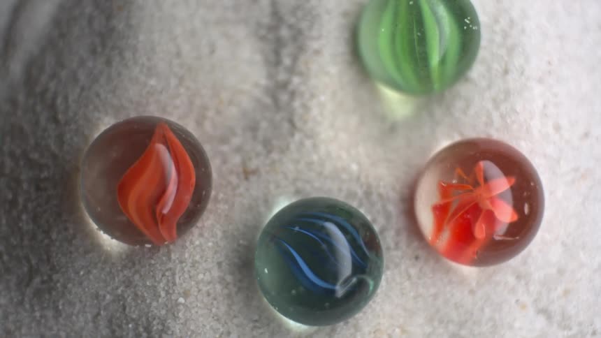 Colorful glass marbles displayed over a shiny white fabric