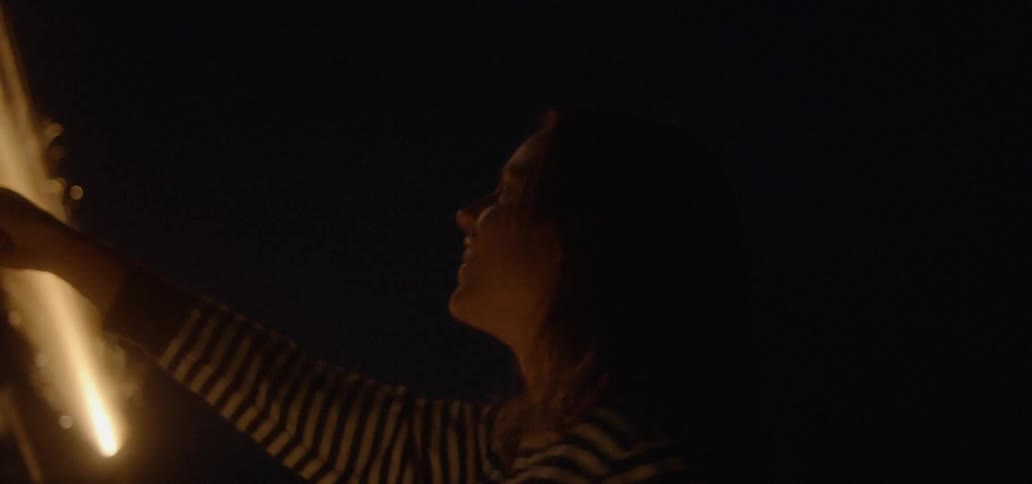 Woman holds a firework outside at night