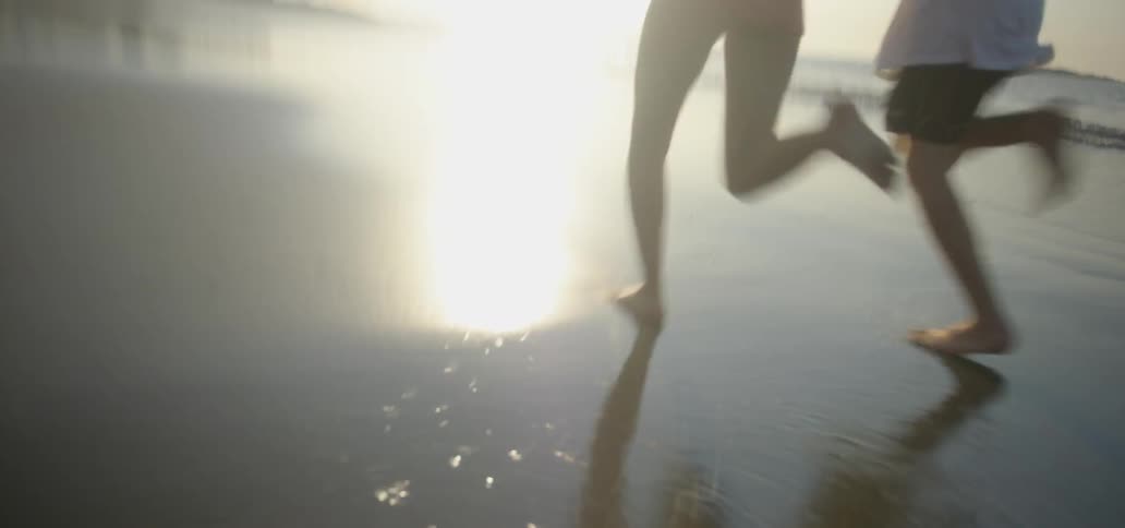 Two people run on the and of the beach
