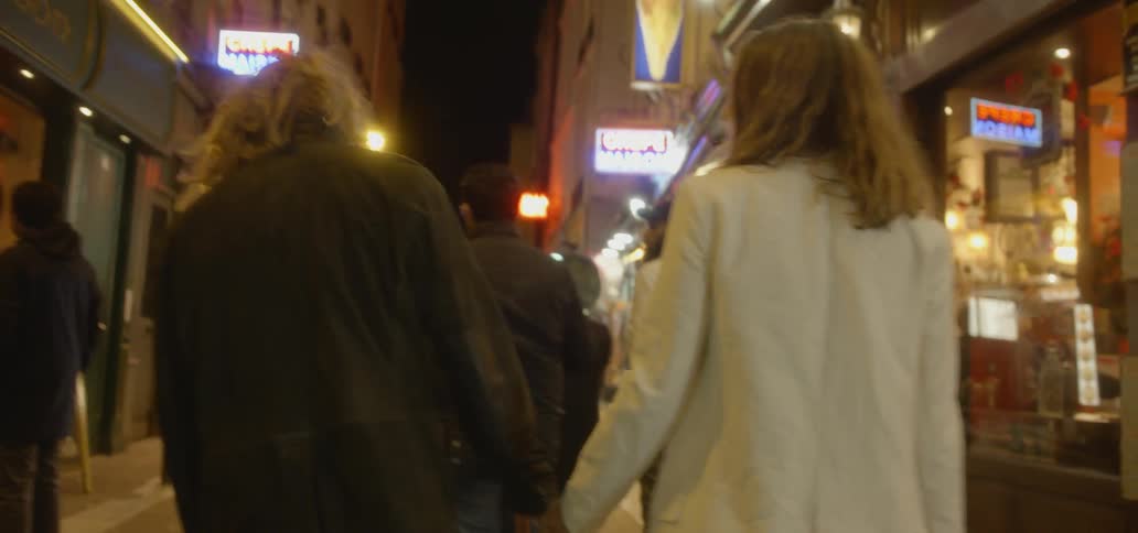 People walk on a city sidewalk at night
