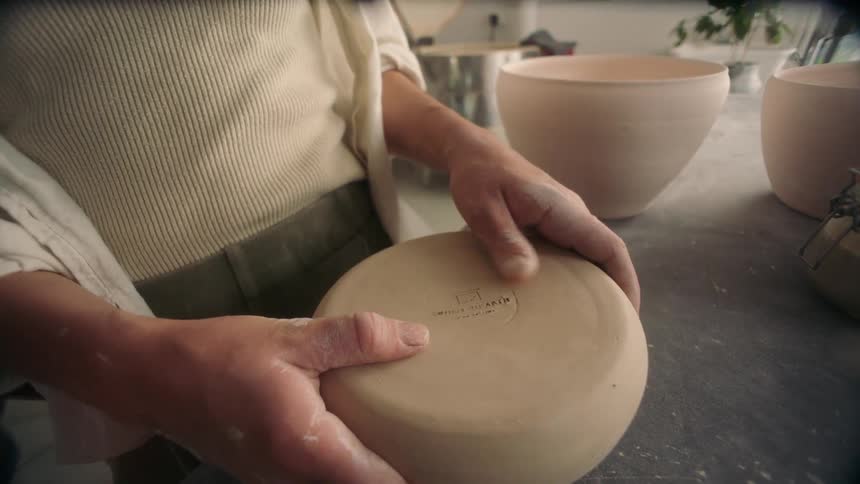Adult hands are rubbing the bottom of a stone bowl