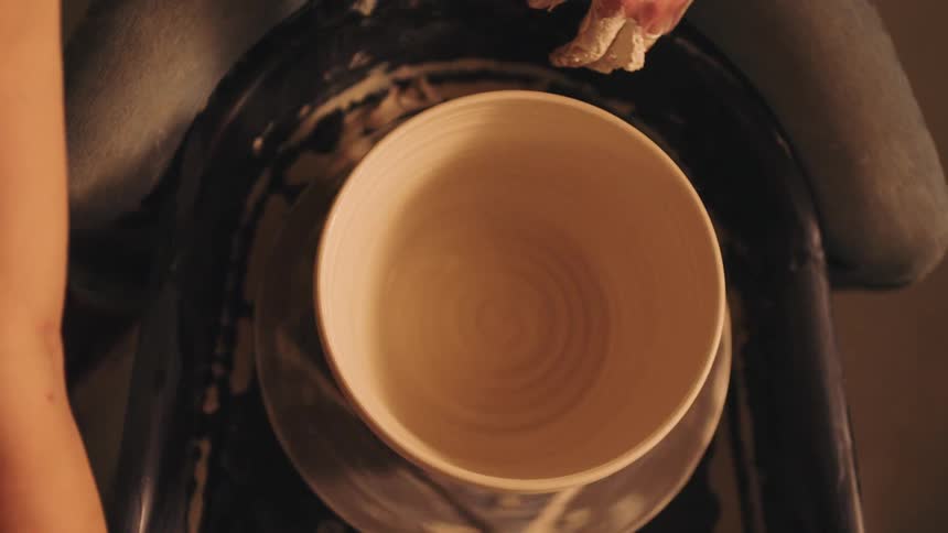 A womans hands make a ceramic bowl on a pottery wheel