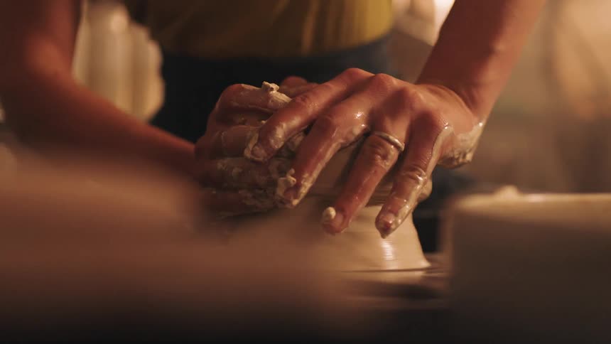 The woman is spinning clay on the pottery wheel