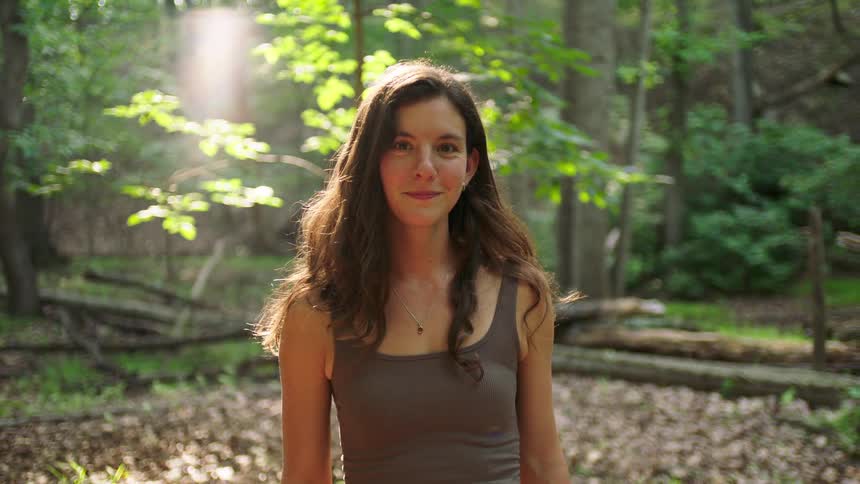 A portrait of a young woman standing outdoors facing forward and a subtle smile