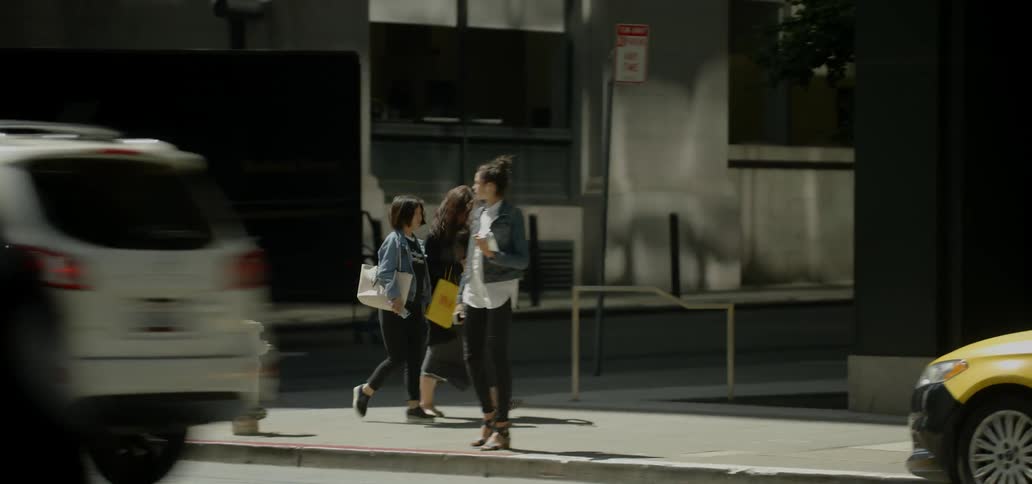 A woman stands at a street corner looking back and forth