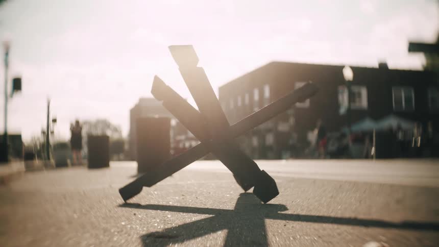 A fourpart object intertwined on an asphalt road with the sun behind it