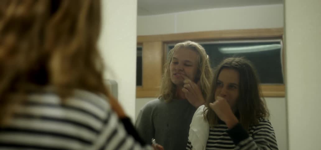 A man and woman brush their teeth