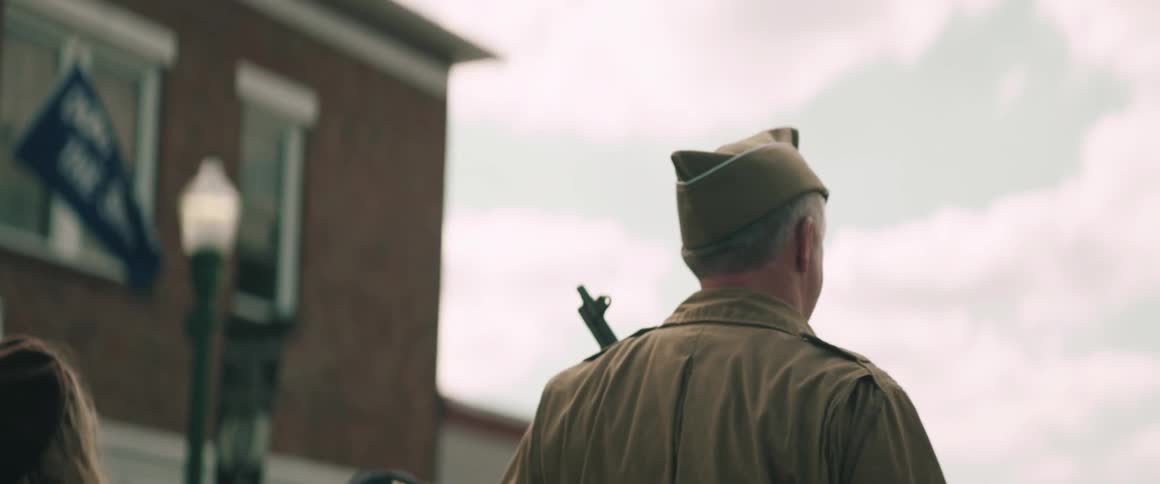 Military personnel with rifle on back walking through urban area