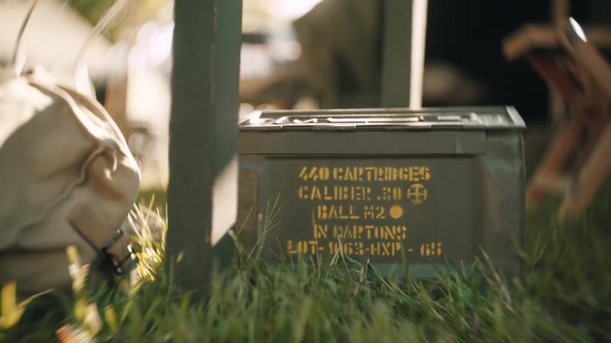 Box of ammo sits on the grass in camp on a sunny day