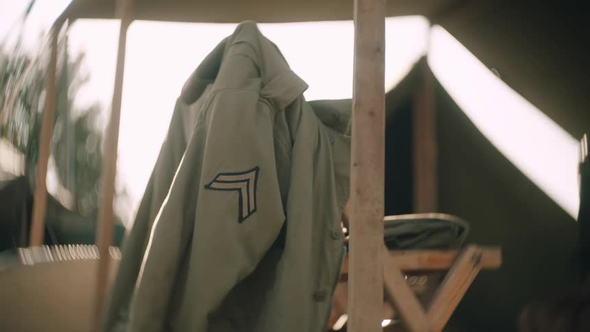 The military jacket is hanging on the chair by the tent