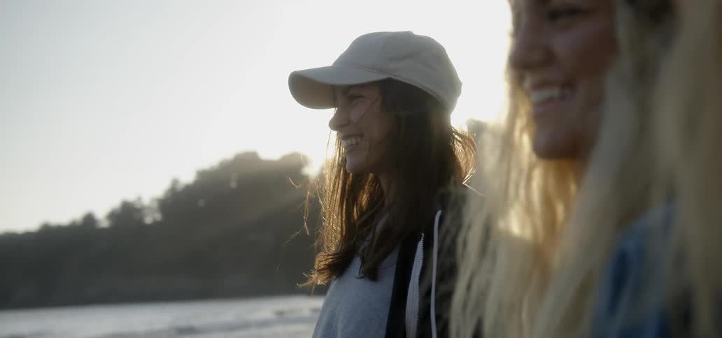 Two women talk and smile on a beach