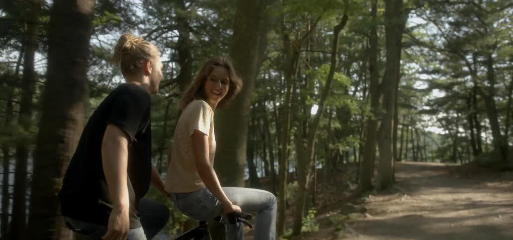 Man riding a bicycle with woman sitting on handlebars