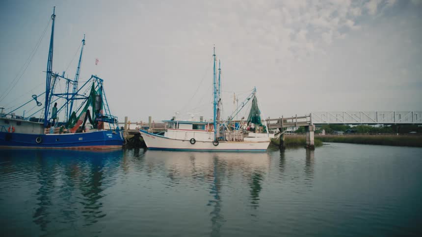 Two boats docked side by side in a harbor at midday