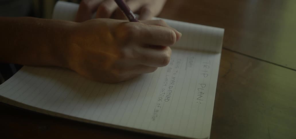 Person writes in a notebook on a desk