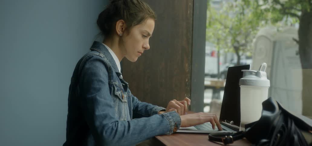 A woman working on her laptop by a window