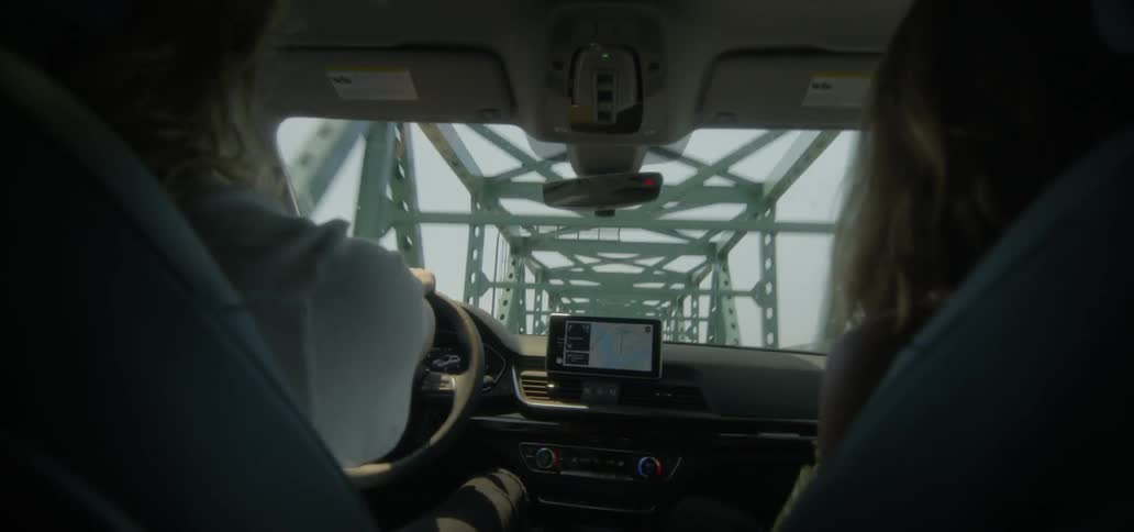 Two people drive over a bridge