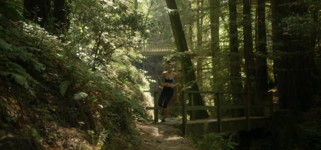 Woman runs across a wooden bridge in the woods