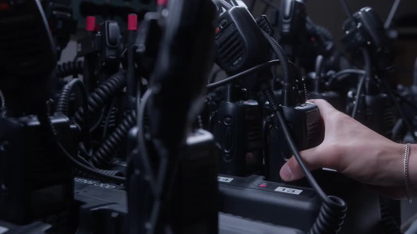 The person picks up a walkie talkie from the charger