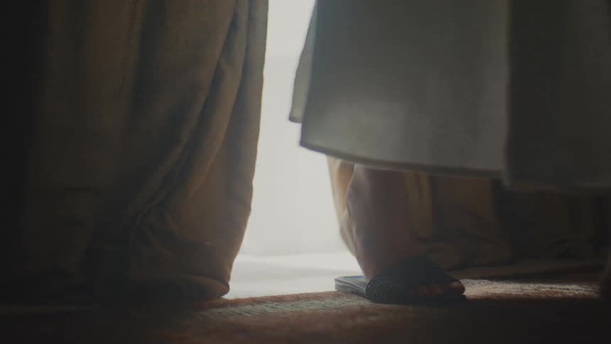 The woman walks through the curtains in front of the doorway