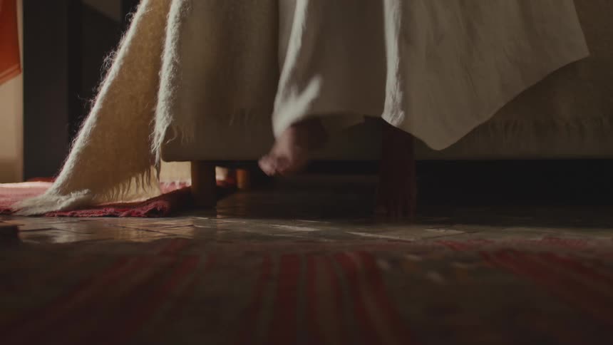 Bare feet partially visible as she climbs onto the bed